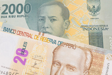 A macro image of a grey two thousand Indonesian rupiah bank note paired up with a beige, twenty sol bill from Peru.  Shot close up in macro.