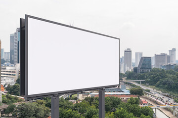 Obraz premium Blank white road billboard with KL cityscape background at day time. Street advertising poster, mock up, 3D rendering. Side view. The concept of marketing communication to promote or sell idea.