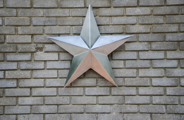 close-up of a steel silver star on a gray brick wall.copy space