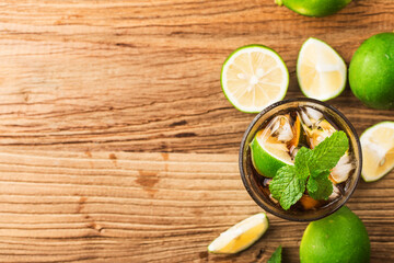 Fresh made Cuba Libre with brown rum, cola, mint and lemon on wooden background