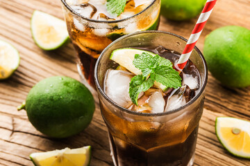 Fresh made Cuba Libre with brown rum, cola, mint and lemon on wooden background