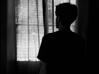 man alone looking through the brown curtain - depressive loneliness -  closed window - hiding from the world - dark  - out window 