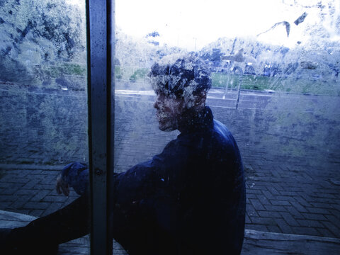 Man sitting behind a blurred glass - introvert man - phobia social - depressive man