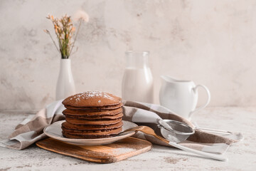 Plate with delicious chocolate pancakes on light background