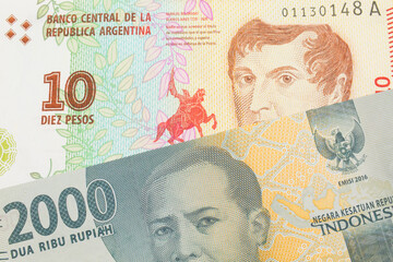 A macro image of a grey two thousand Indonesian rupiah bank note paired up with a colorful ten peso note from Argentina.  Shot close up in macro.