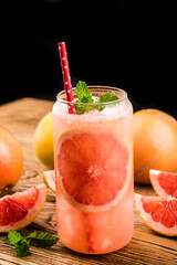 A glass of ripe grapefruit with juice on wooden table close-up