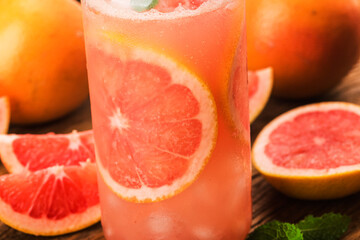 A glass of ripe grapefruit with juice on wooden table close-up