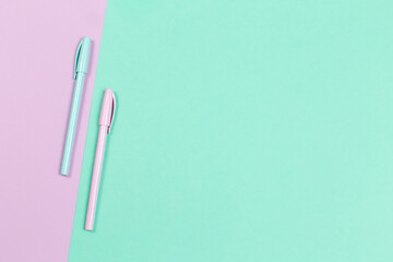 Two pens on a violet and turquoise background.
