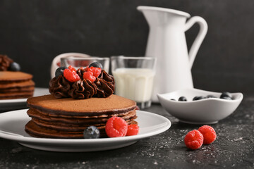 Plate with delicious chocolate pancakes and berries on dark background