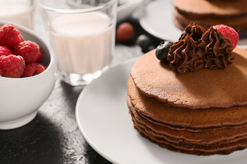 Plate with delicious chocolate pancakes and berries on table