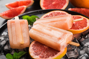 Red grapefruit homemade popsicles with ice cubes.