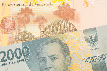 A macro image of a grey two thousand Indonesian rupiah bank note paired up with a colorful, yellow five Bolivar bank note from Venezuela.  Shot close up in macro.