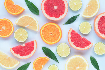 Various sliced citrus fruits: lime, orange, red and yellow grapefruit with green leaves on a white background, texture