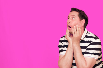 Caucasian man wearing casual striped t-shirt standing over isolated hot pink background shows...