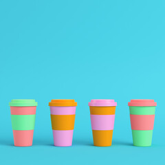 Four colorful coffee cups on bright blue background in pastel colors. Minimalism concept