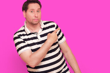 Caucasian man wearing casual striped t-shirt standing over isolated hot pink background shows...