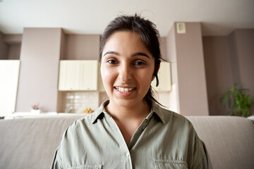Smiling indian woman online teacher, sales agent, remote tutor or call center operator wearing headset look at webcam zoom conference video call at home office. Headshot portrait. Webcamera view.