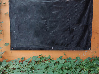 Empty Hanging black banner on wall and green leaf