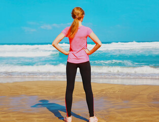 Fitness woman doing exercises on the beach near the sea at summer day