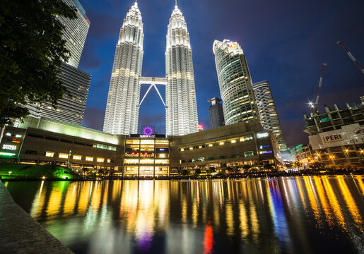 KUALA LUMPUR, MALAYSIA - NOVEMBER 10, 2015: The Petronas twin towers reflect in the pond in the KLCC park, which is lined with luxury hotels and shopping mall in Kuala Lumpur at night.