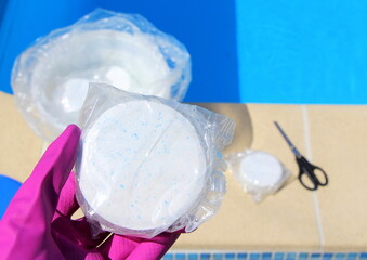 White big chlorine tablet in the hand of a service worker for disinfection of swimming pools. The beginning of the swimming season is hot summer.