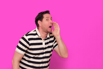 Caucasian man wearing casual striped t-shirt standing over isolated hot pink background shows...