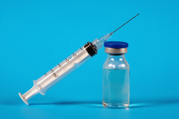 Medicine bottle for injection with syringe for vaccination on the blue background