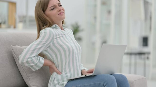 Tired Young Woman with Laptop having Back Pain at Home 