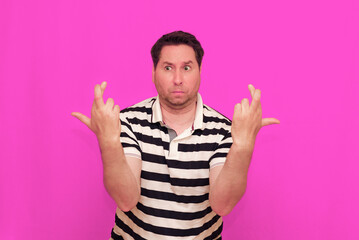 Naklejka premium Caucasian man wearing casual striped t-shirt standing over isolated hot pink background shows various gestures.