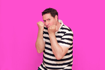 Caucasian man wearing casual striped t-shirt standing over isolated hot pink background shows...