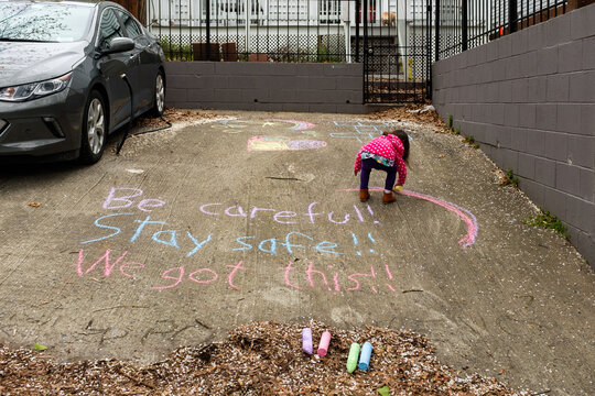 Little girl coloring with chalk during coronavirus social distancing