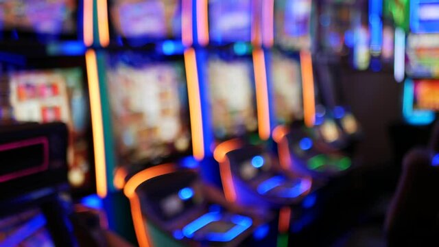 Defocused slot machines glow in casino on fabulous Las Vegas Strip, USA. Blurred gambling jackpot slots in hotel near Fremont street. Illuminated neon fruit machine for risk money playing and betting.