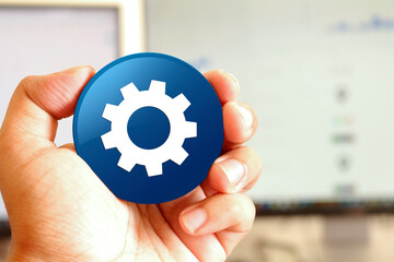 Process icon blue round button holding by hand infront of workspace background
