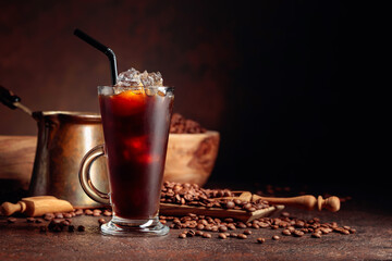 Ice coffee in frozen glass and coffee beans on a old brown table with kitchen utensils.