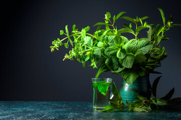 Mint tea and bunch of fresh mint in an old ceramic pot.