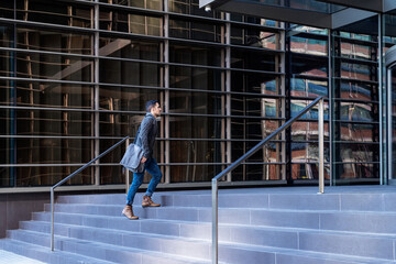 Young bearded man walking upstairs to workplace in an office building