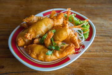 A large crispy fried prawns deep fried in a red dish and dipping special sauce of the restaurant.