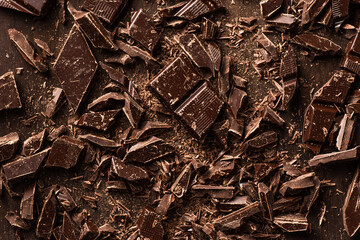 Dark chocolate chopped on dark wooden background. Overhead view.