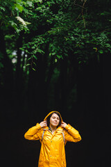 woman in yellow raincoat walking by rainy forest