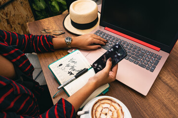 girl checking her phone while working on a coffee shop balcony