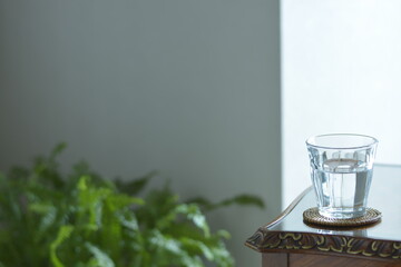 put a mineral water on a antique mahogany table. window is bright.  This expensive furniture is made in England.  blurred background with copy space.