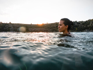 young pretty woman swimming in lake water on sunset