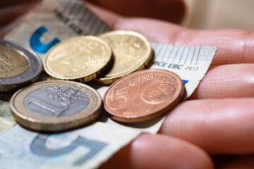 Euro coins and bills in hands, extreme close-up view