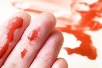 hands in blood and blood on a white surface in the background
