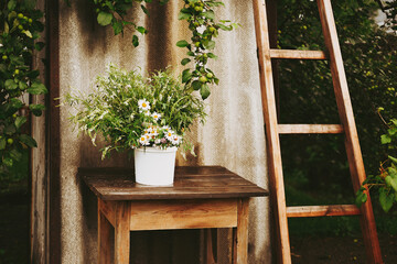 A bouquet of wildflowers and chamomiles on a wooden table. Flowers on a wooden table, rustic bouquet Authentic style