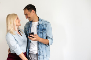 Beautiful, pretty, cute woman and handsome man in shirts writing sms through 3g internet on smart phones over grey background