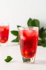 Summer delicious refreshing cherry compote with pulp and with ice in glasses on a white background