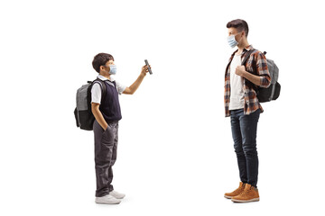 Schoolboy wearing a protective face mask and showing mobile phone to a teenager