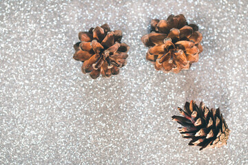 Three pine cones on a silver surface