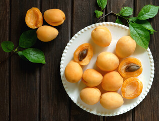 Top view of fresh apricots on a white plate on vintage wooden background